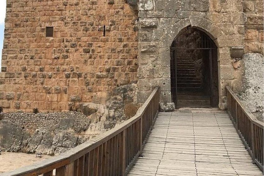 Un puente de piedra con pasarela de madera que conduce a una entrada en arco. 2