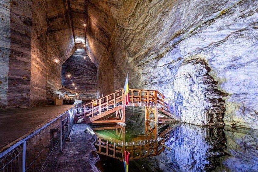 A cave with a wooden staircase and a reflective water surface. 3