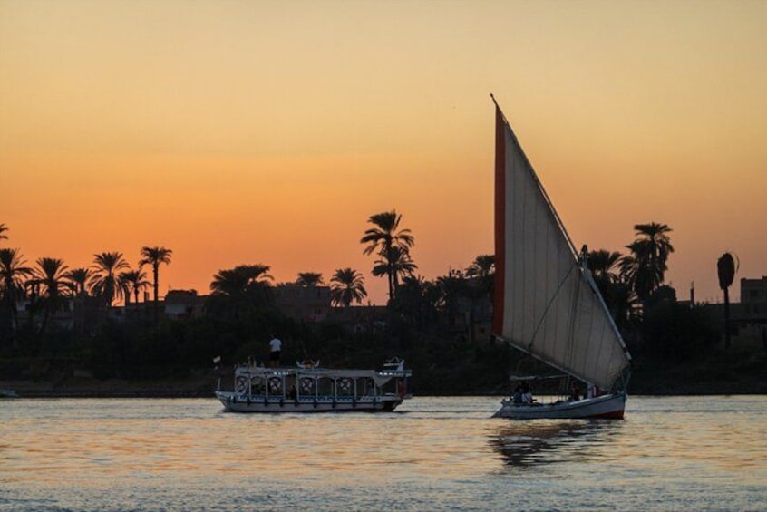 A sunset with a sailboat and a motorboat on calm water, palm trees in the background, and a silhouette of buildings. 2
