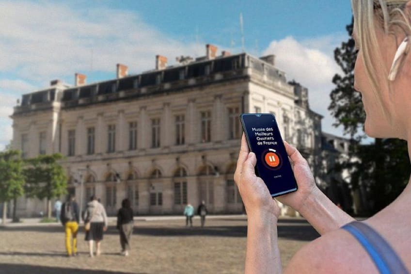 A person holding a smartphone with an app interface in front of a historic building. 4
