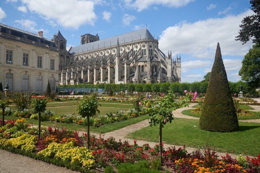 A historic building with intricate architecture, a well-maintained garden with colorful flowers, and a clear sky. 2