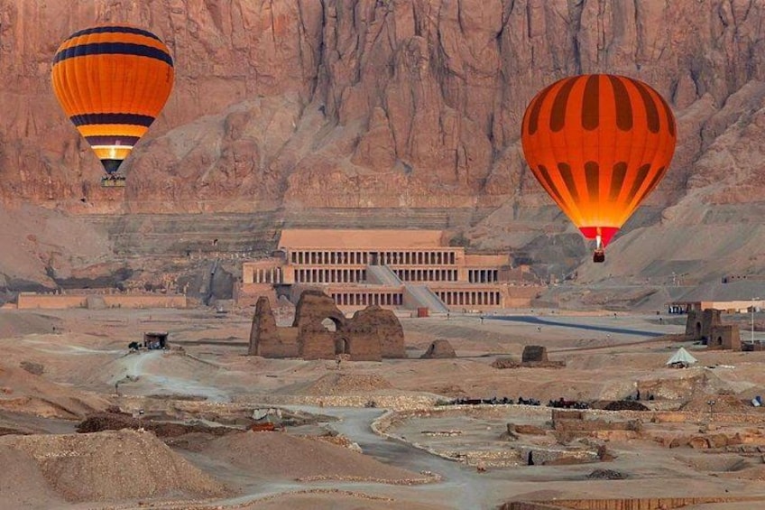 Wüstenlandschaft mit Pyramiden, einem Gebäude und zwei Heißluftballons. 1