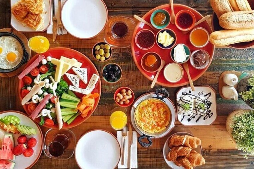 A variety of breakfast foods including eggs, bread, fruits, and condiments on a wooden table. 5