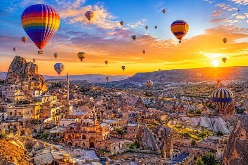 A cityscape with hot air balloons, a prominent minaret, and rocky terrain. 1