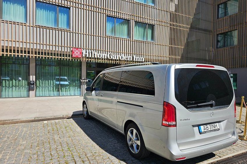 A silver van parked in front of a building with a Hilton Garden Inn sign. 1