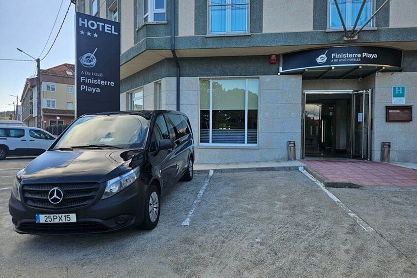 A black Mercedes-Benz SUV parked in front of a hotel named Finisterre Playa. 4