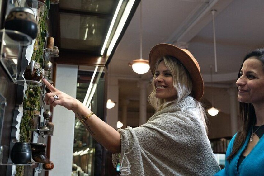 A person pointing at a display of various glassware and bottles. 1