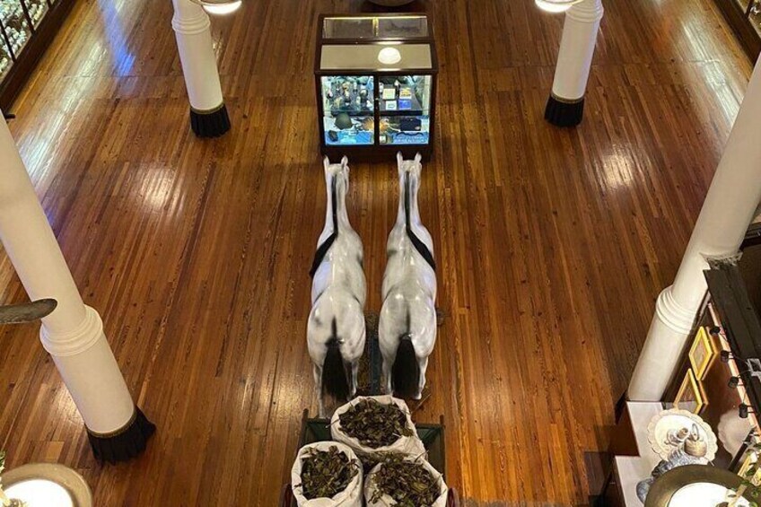 A wooden floor with two white statues of horses facing each other, surrounded by potted plants. 2
