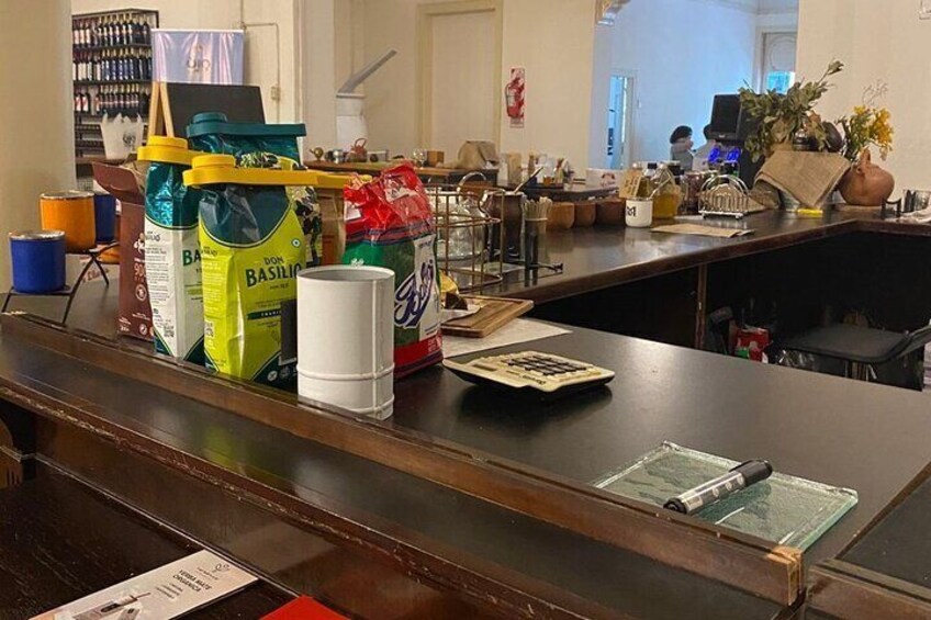 A counter with bags of basil, a white cup, and a calculator. 5