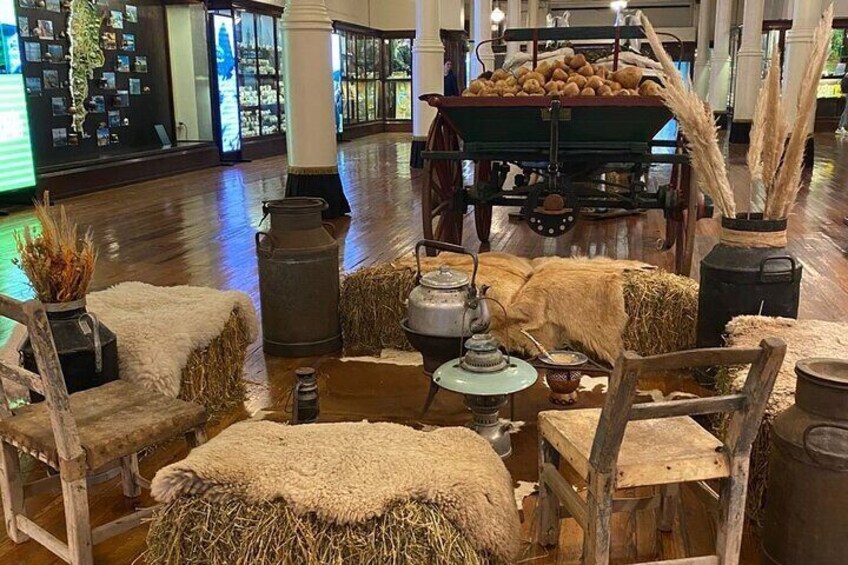 A rustic interior with wooden furniture, hay bales, and vintage farm equipment. 4
