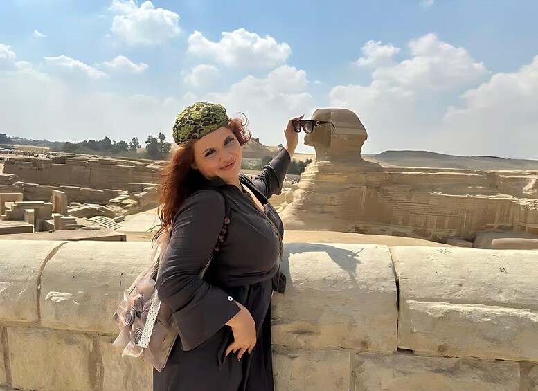 Una persona fotografiando una gran estructura de piedra con un paisaje desértico al fondo. 1