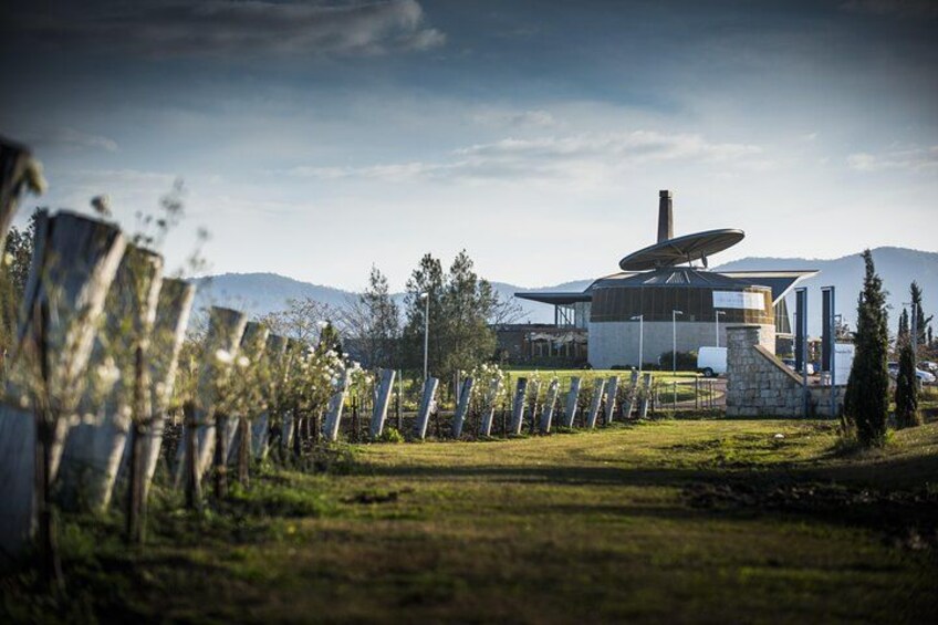 A modern building with a satellite dish, surrounded by a fence and trees, with mountains in the background. 5