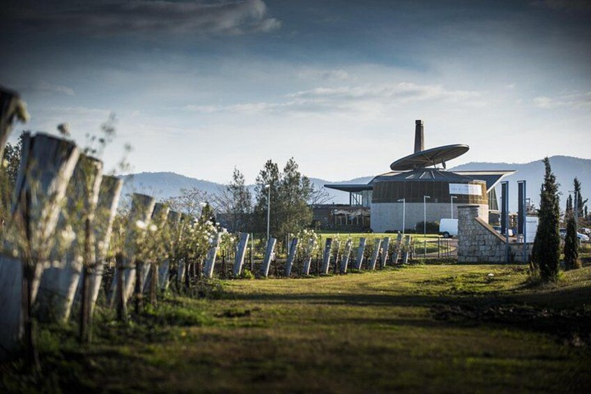 A modern building with a satellite dish, surrounded by a fence and trees, with mountains in the background. 5