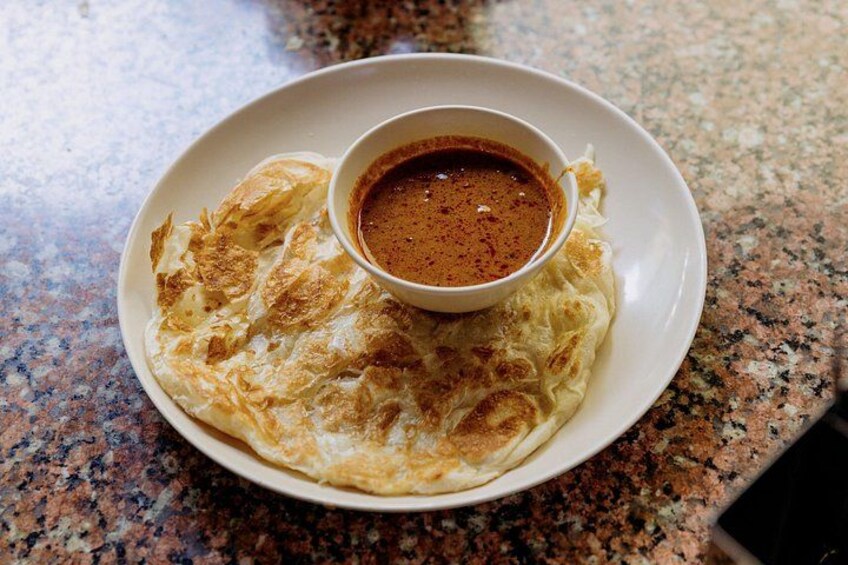 Ein Teller mit einem gefalteten Crêpe und einer kleinen Soßenschale. 2