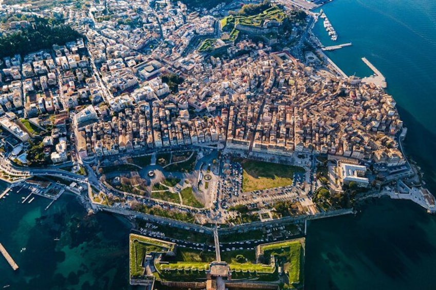 An aerial view of a coastal city with a dense urban area, a fortified wall, and a harbor. 4