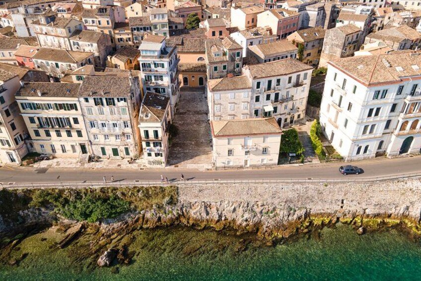 An aerial view of a coastal town with buildings, a road, and a rocky shoreline. 2