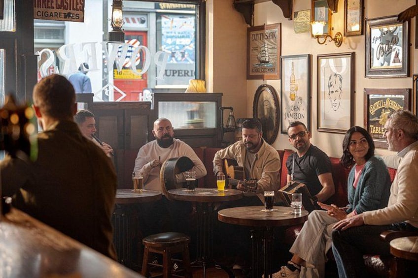 A group of people sitting at a bar in a pub with various posters and signs on the walls. 2