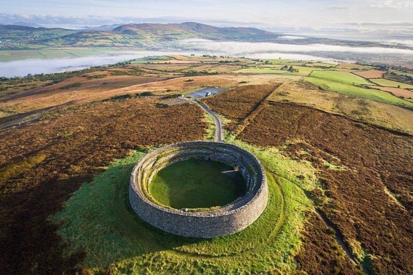 A circular stone structure surrounded by a grassy field with a path leading to it. 5