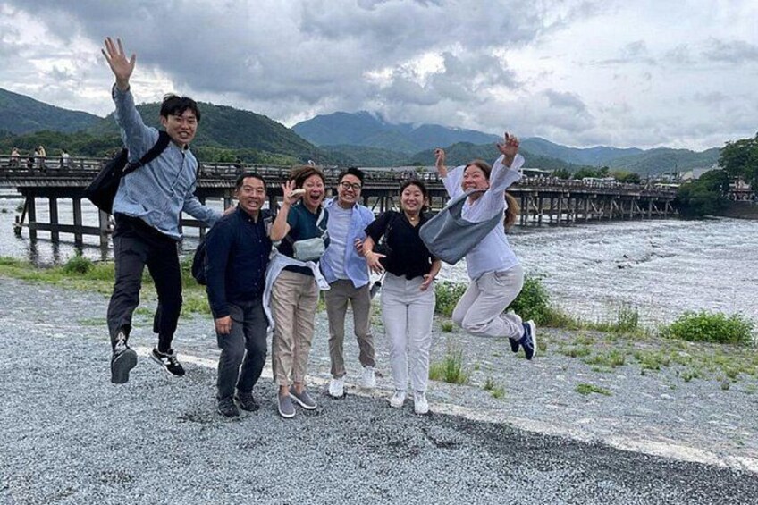 A group of people jumping in front of a river with mountains in the background. 4