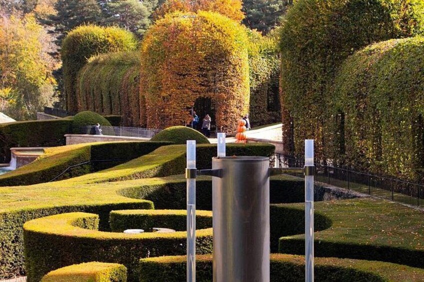 A well-manicured garden with geometric hedges, a metal sculpture, and a pathway. 3