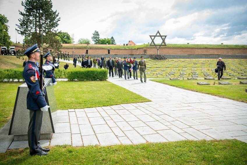 Militær ceremoni med uniformerede soldater, en Davidstjerne og en kirkegård i baggrunden. 4