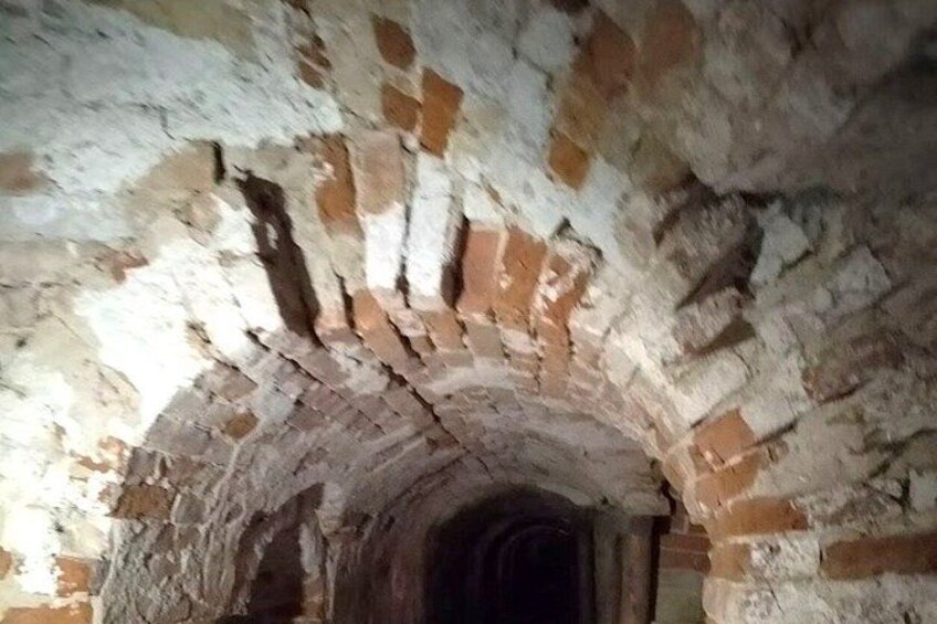 An arched brick structure with visible wear and discoloration. 2