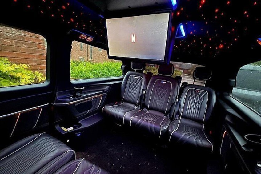 A vehicle interior with leather seats, a central entertainment screen, and ambient lighting. 2