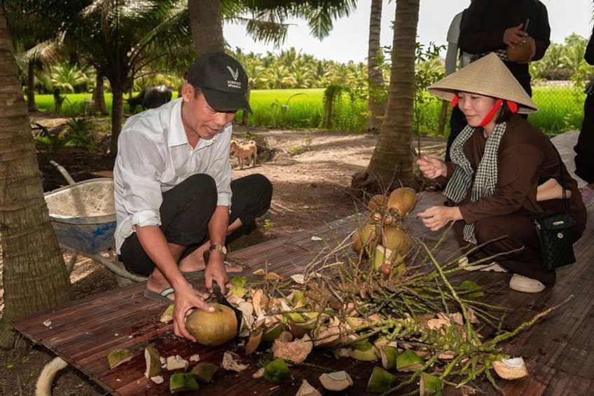 Two people working with coconuts on a wooden platform in a rural setting. 3