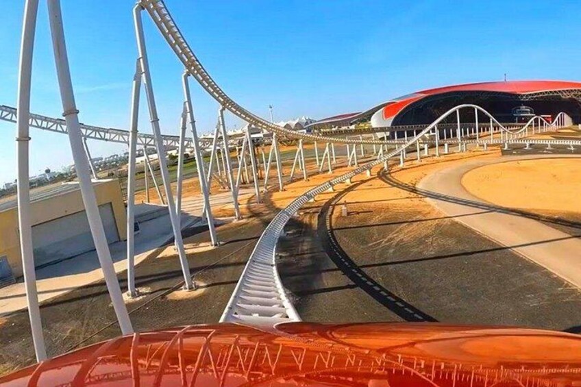 A roller coaster track with a loop, a stadium, and a clear sky. 2