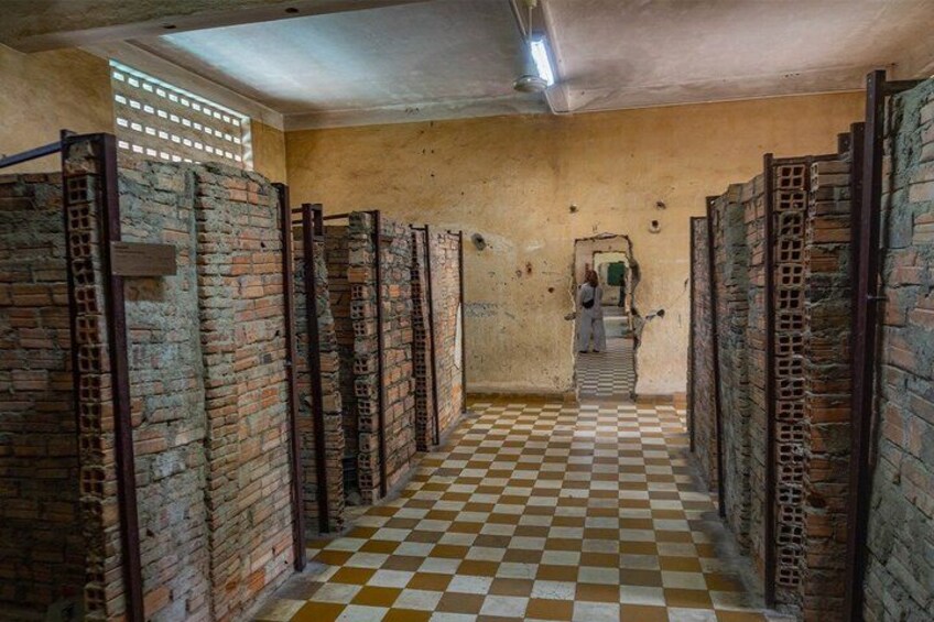 A corridor with brick walls and a checkered floor, leading to a door at the end. 3