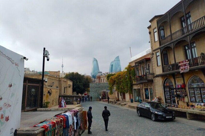 A cobblestone street with buildings, a black car, and a person walking. 3
