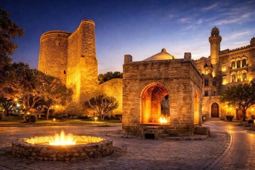 A historic castle with a round tower, a courtyard with a fire pit, and a small building with an arched entrance. 1