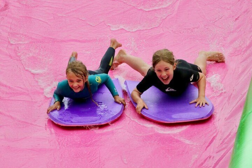 Deux personnes glissent sur un toboggan rose. 3