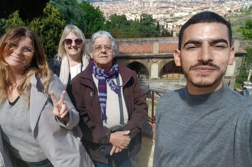Eine Gruppe von Menschen steht auf einer Terrasse, im Hintergrund ist eine Stadtansicht zu sehen. 5