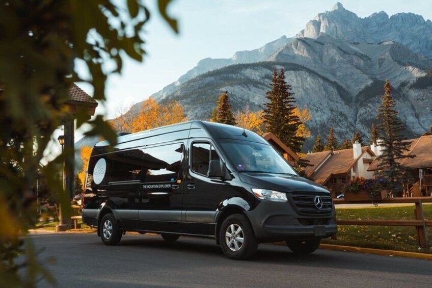 A black Mercedes-Benz Sprinter van parked on a road with a mountainous backdrop. 1