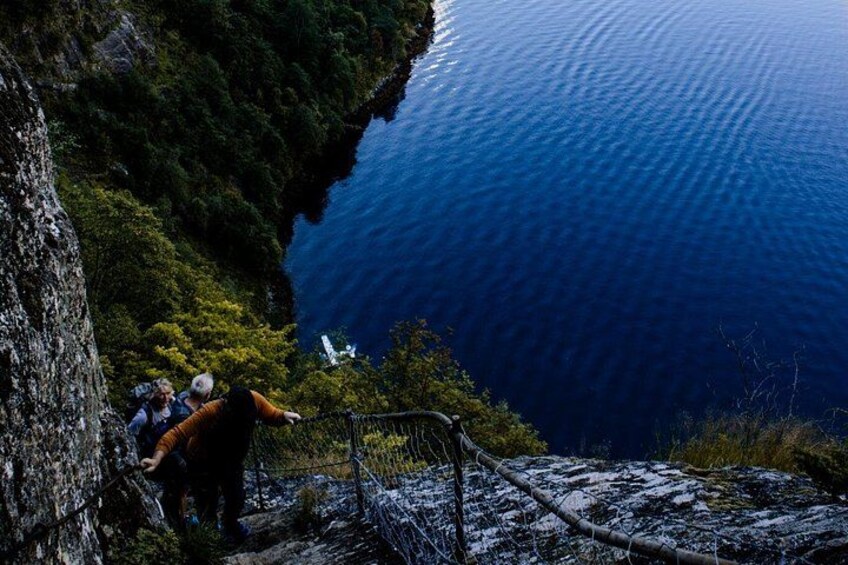 Una persona asciende por un sendero rocoso con vista a una extensión de agua azul intenso. 3