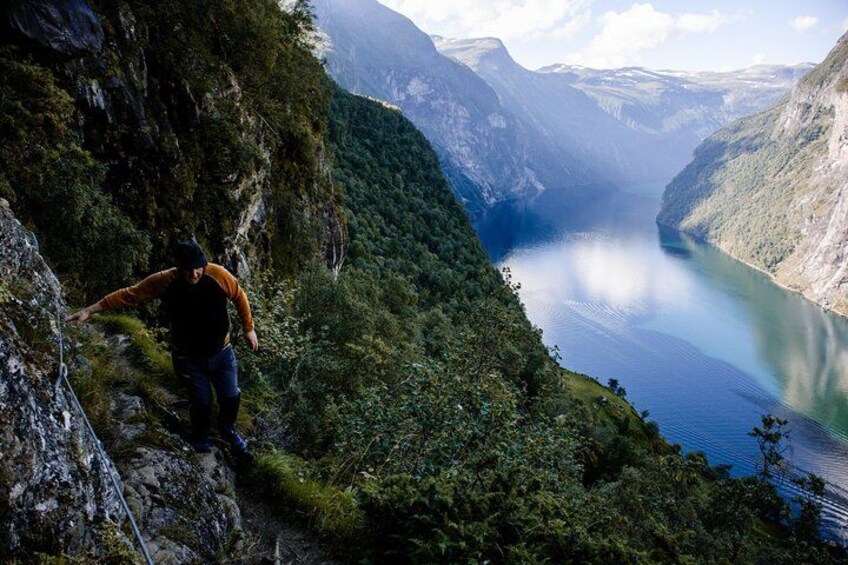 A hiker on a mountain trail overlooking a lake. 1