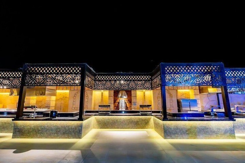 A well-lit outdoor area with a pool, lounge chairs, and a decorative gazebo structure. 5