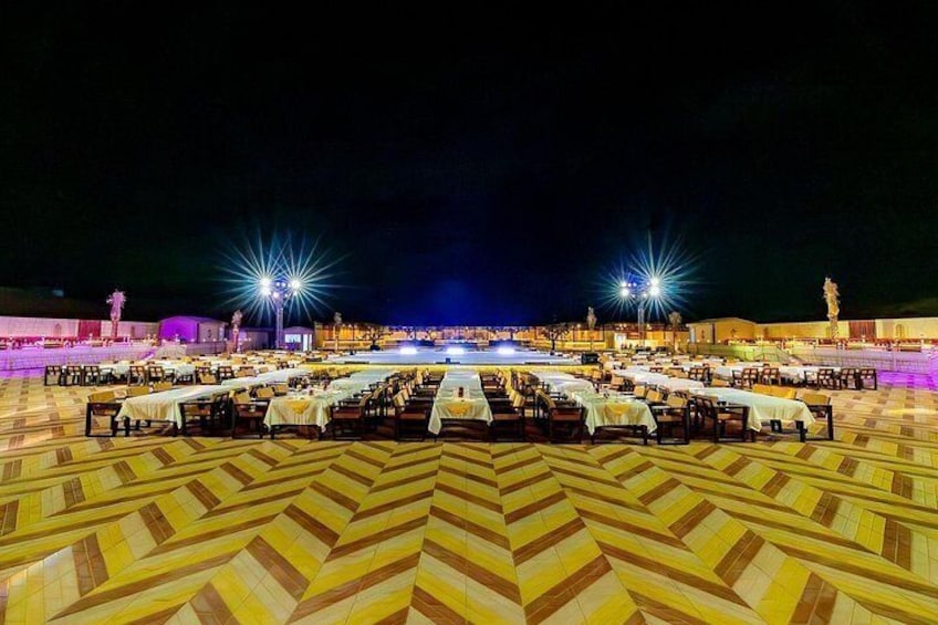 An outdoor dining area with tables arranged in a circular pattern, illuminated by overhead lights. 4