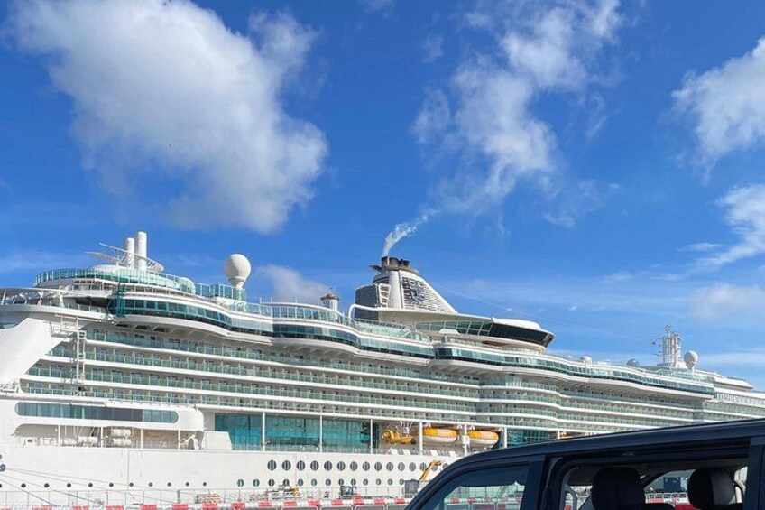 A large cruise ship docked at a port with multiple decks and a clear blue sky in the background. 1