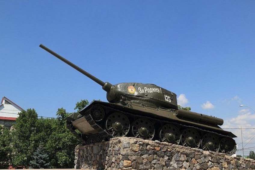 A military tank with the inscription 'За Родину' on its turret, positioned on a stone pedestal. 4