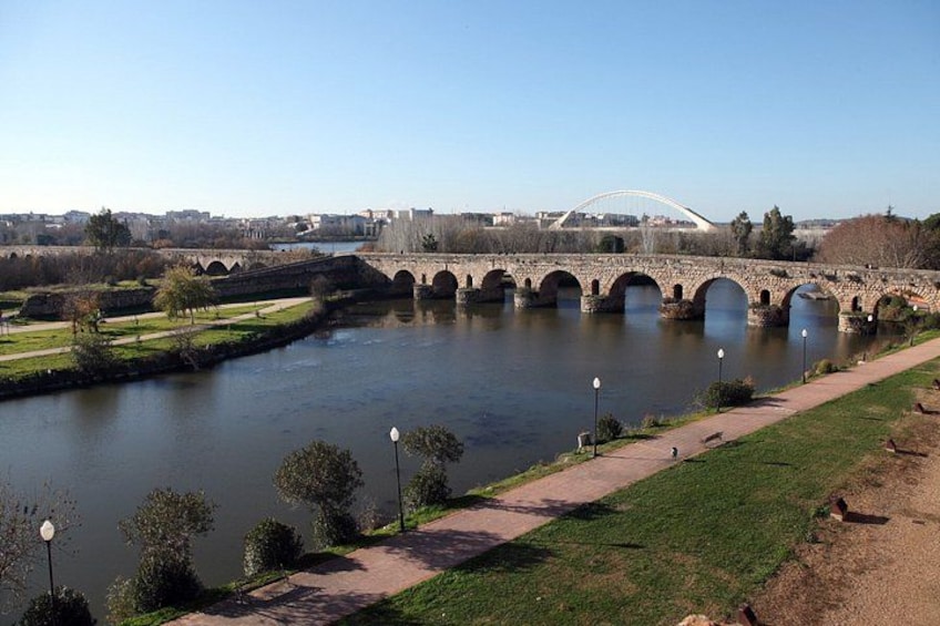 A river with a stone bridge, a modern bridge, and a pathway along the riverbank. 3