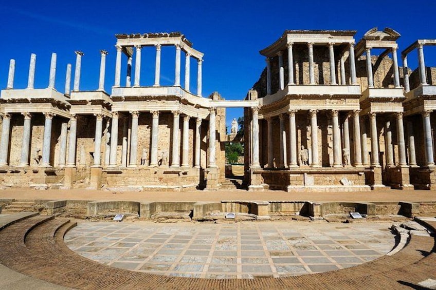Ancient ruins with columns and a circular stone floor. 5