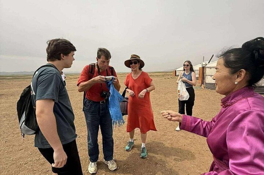 Een groep mensen staat in een kaal landschap, met tenten op de achtergrond. 3