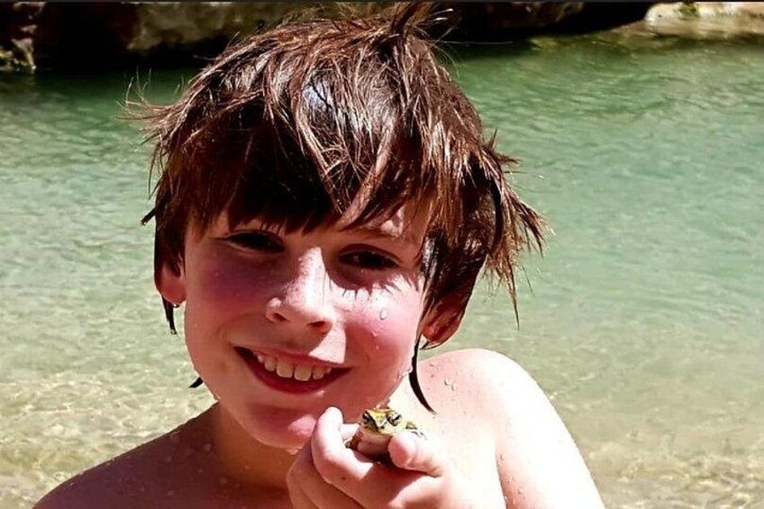 A child holding a small object near a body of water. 3