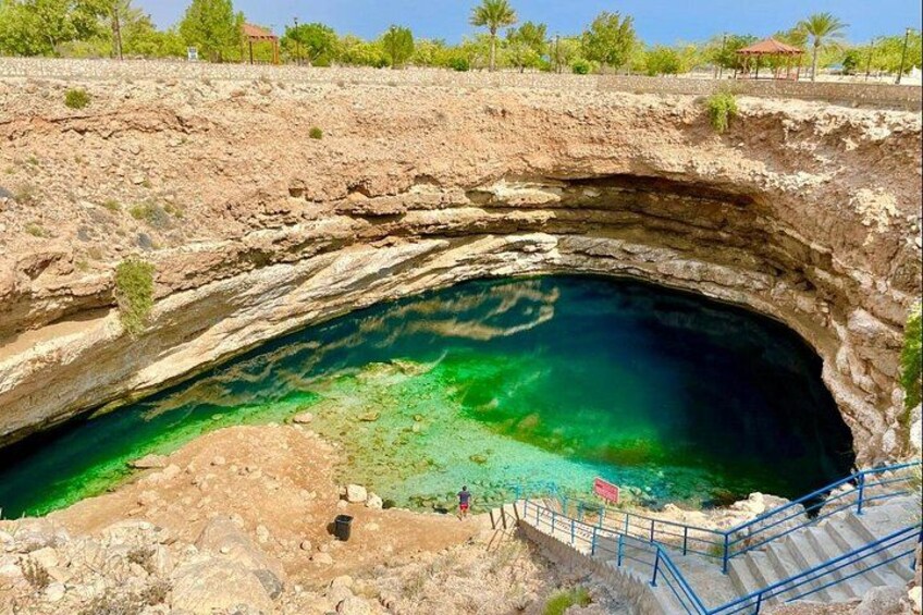 A natural rock formation with a clear blue pool at the bottom. 5