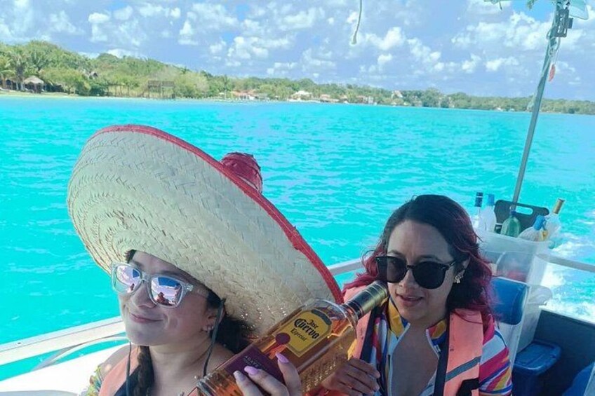 Dos personas en un bote con un mar turquesa y colinas verdes al fondo. 5