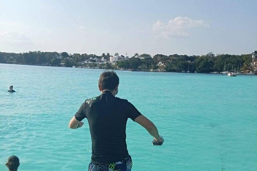 Una persona de pie en un bote, mirando un mar tranquilo con una costa lejana. 3