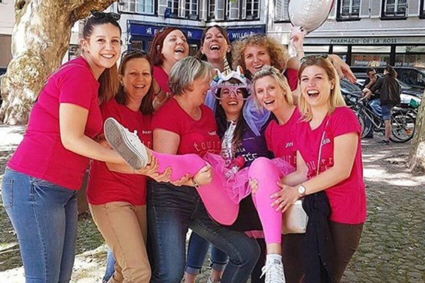 A group of people in red shirts gathered outdoors, some holding a pink object. 1