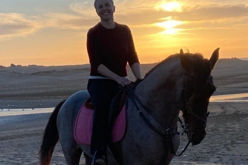 Eine Person reitet bei Sonnenuntergang einen Pferden am Strand. 3